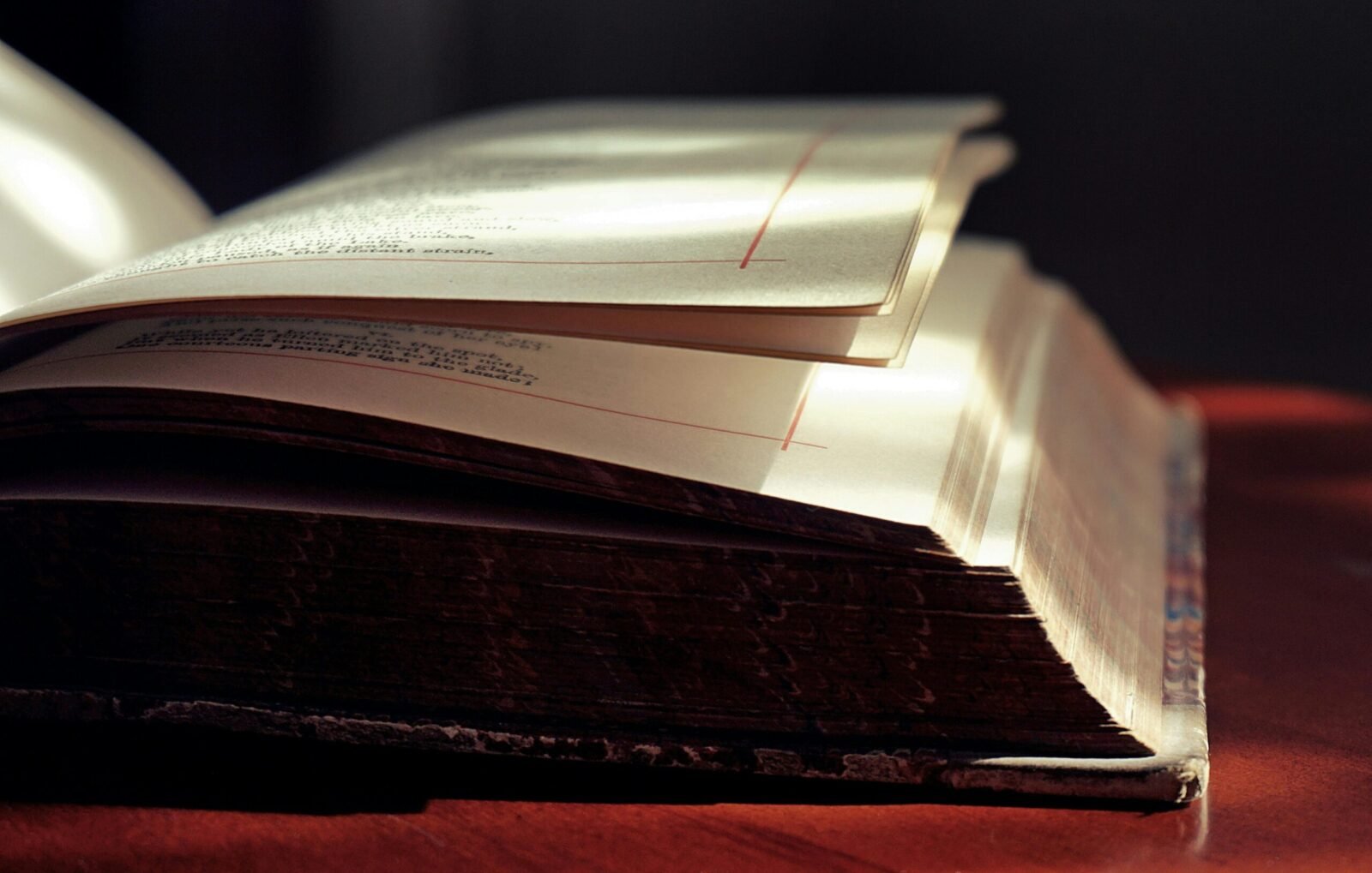 Artistic close-up of an open hardcover book in soft lighting, highlighting the texture of the pages.